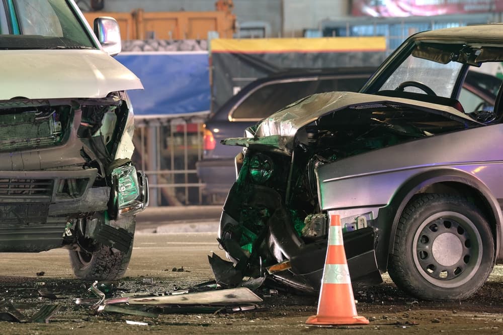 Damaged in heavy car accident vehicles after collision on city street crash site at night