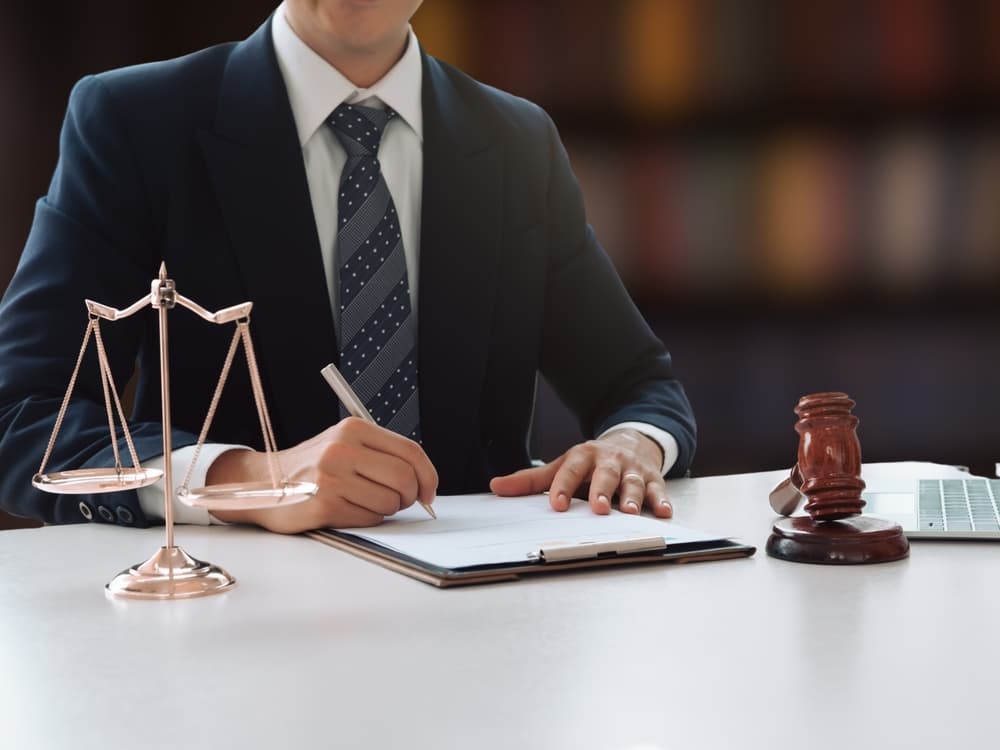 A young judge and a lawyer collaborating at a table indoors, reviewing documents in a professional legal setting.