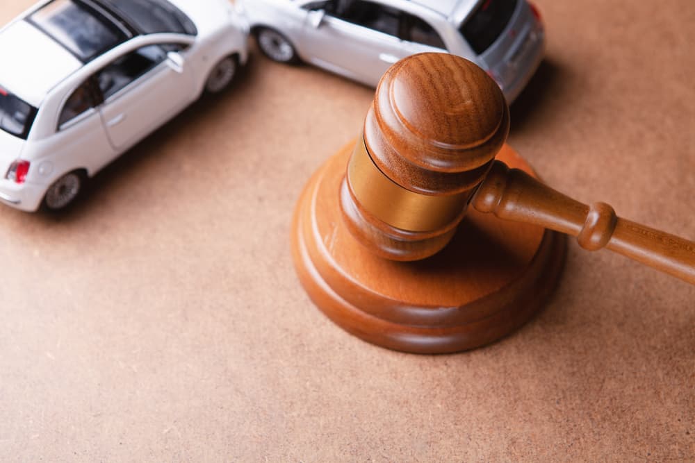 A model car sits next to a gavel, symbolizing accident lawsuits, insurance claims, or court cases involving motor vehicle incidents.