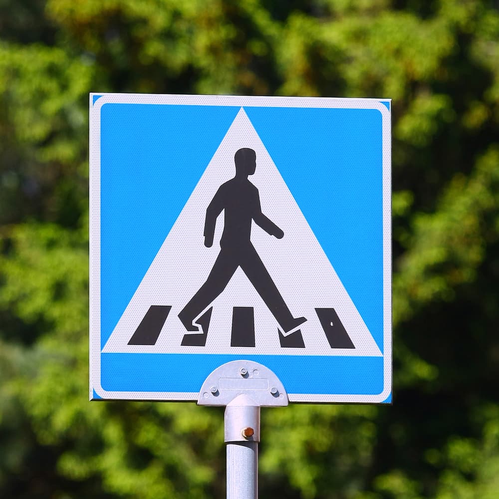 Blue caution road sign featuring a pedestrian symbol.






