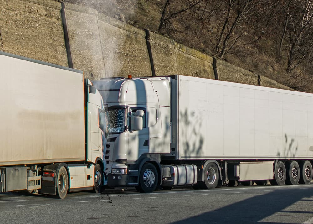 Two semi-trucks collide on a highway, showing damage and smoke, highlighting the need for legal assistance.